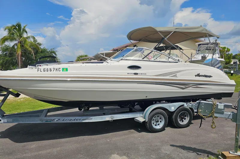 Slide: The Image of 2006 Hurricane SunDeck 237 DC OB boat on trailer, parked outdoors under a cloudy sky. - 2