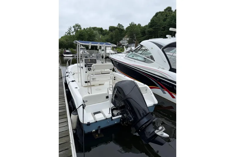 Slide: The Image of 2001 Boston Whaler 21 Outrage boat docked, featuring outboard motor and spacious deck. - 6