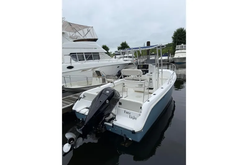 Slide: The Image of 2001 Boston Whaler 21 Outrage boat docked, featuring a sleek design and powerful outboard motor. - 4