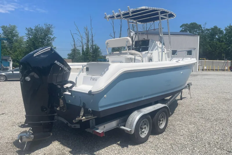 Slide: The Image of 2001 Boston Whaler 21 Outrage boat on trailer, featuring a Mercury outboard motor. - 2