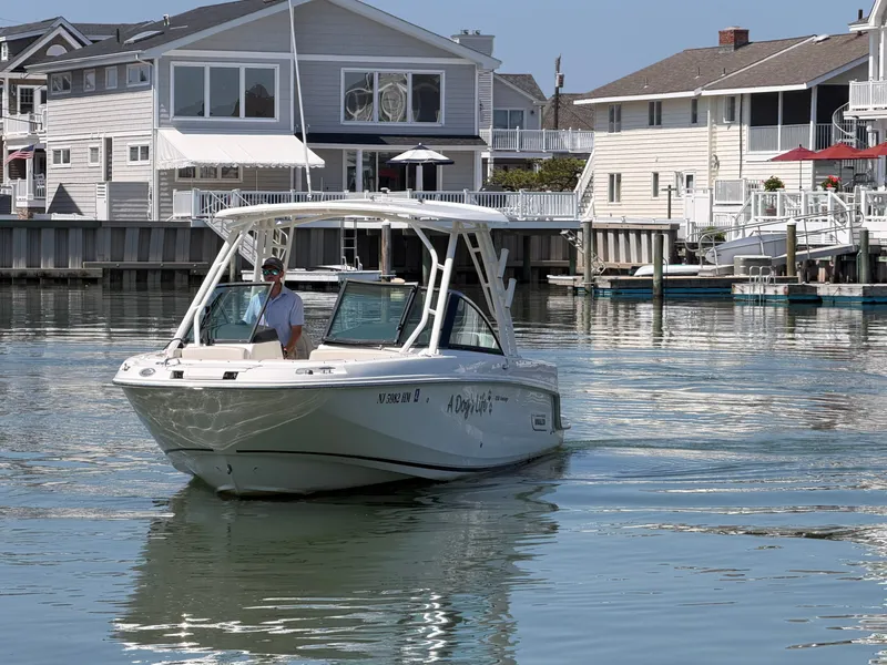 Slide: The Image of A 2018 Boston Whaler 230 Vantage cruising on calm water in front of modern houses. - 29