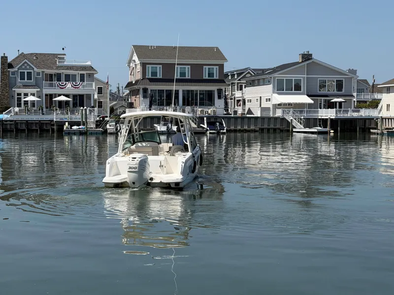 Slide: The Image of A 2018 Boston Whaler 230 Vantage on calm water near coastal houses. - 27