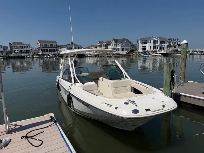 Slide: The Image of A 2018 Boston Whaler 230 Vantage docked in a calm harbor with houses in the background. - 25