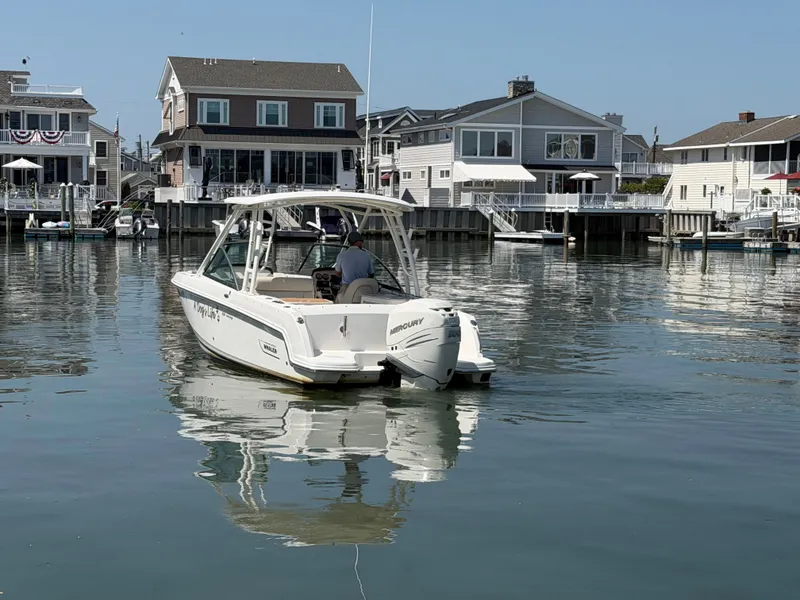 Slide: The Image of A 2018 Boston Whaler 230 Vantage on calm water near a coastal town. - 26