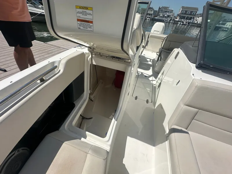 Slide: The Image of The image shows the cockpit of a 2018 Boston Whaler 230 Vantage with an open storage hatch. - 21