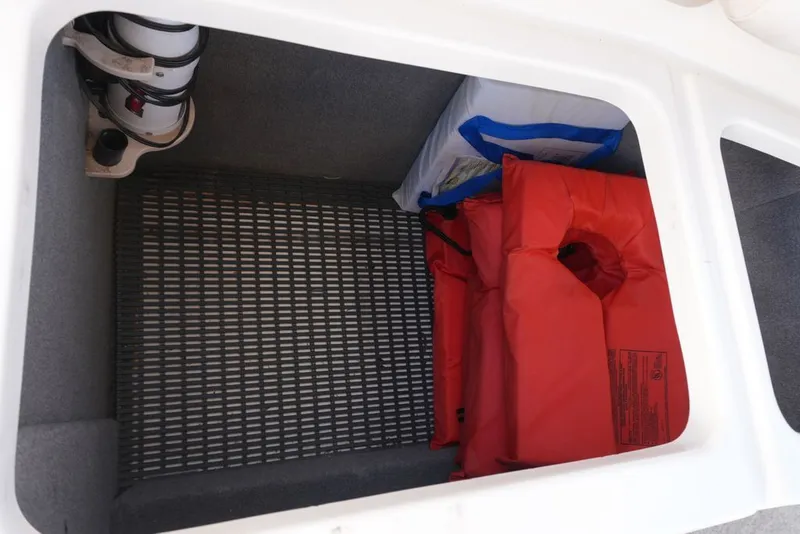 Slide: The Image of A storage compartment in the boat with an orange life jacket and a blue bag. - 24