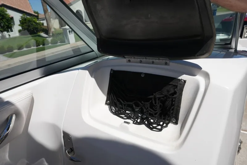 Slide: The Image of An open storage compartment with a net inside a 2008 Chaparral 264 Sunesta boat. - 14