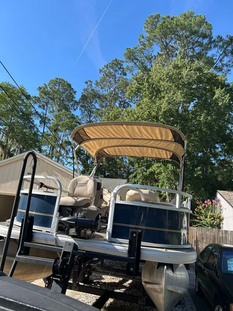 Slide: The Image of A 2023 Sun Tracker Bass Buggy pontoon boat on a trailer in a yard. - 18