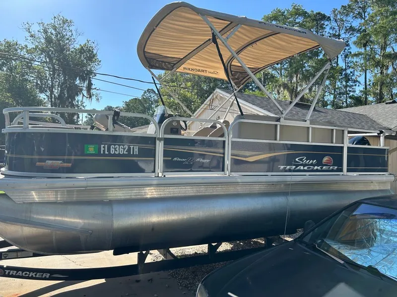The Image of A 2023 Sun Tracker Bass Buggy pontoon boat with a sunshade, parked on a trailer. - 0