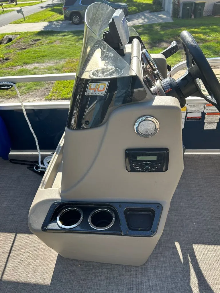 Slide: The Image of The image shows the helm of a 2023 Sun Tracker Bass Buggy with a steering wheel and cup holders. - 3