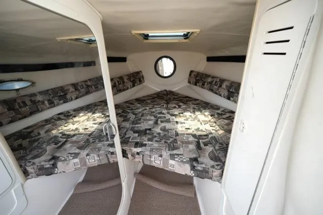 Slide: The Image of 2002 Rinker 276 Captiva Cuddy cabin interior with patterned cushions and porthole window. - 14