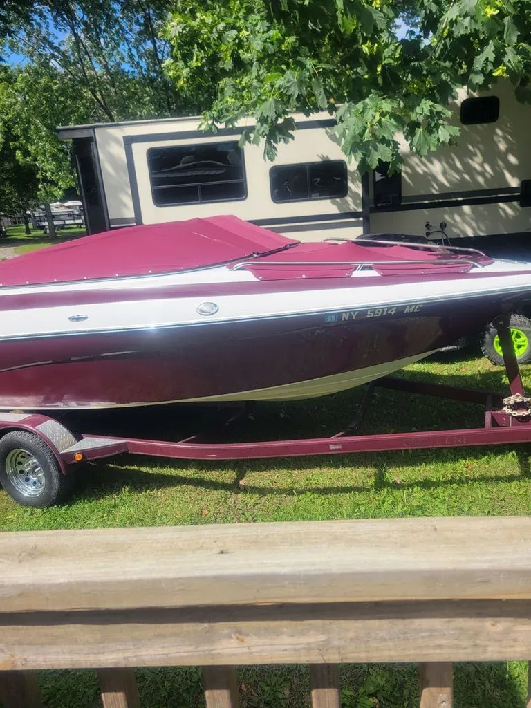 The Image of A 2005 Crownline 192 BR boat on a trailer, surrounded by trees and a camper. - 0