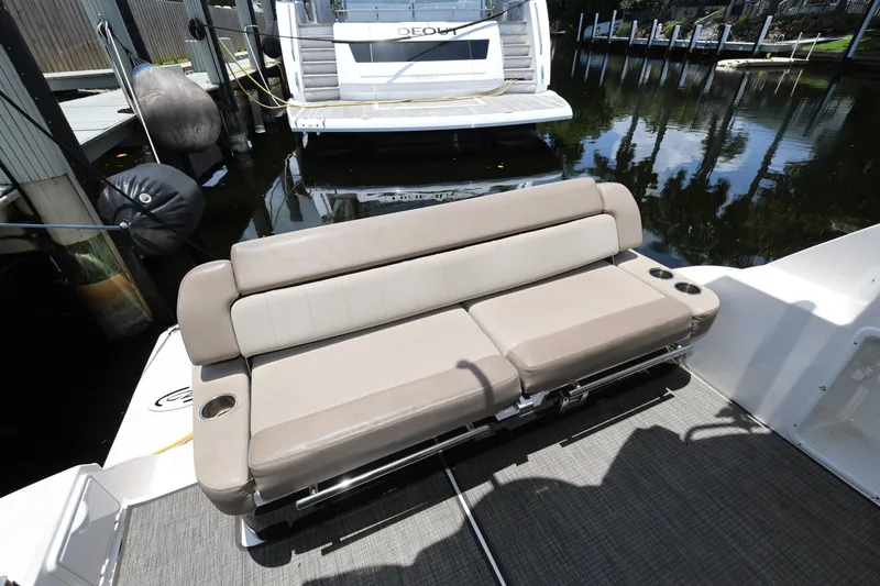Slide: The Image of 2015 Regal 35 Sport Coupe boat with beige seating and cup holders, docked by the water. - 7