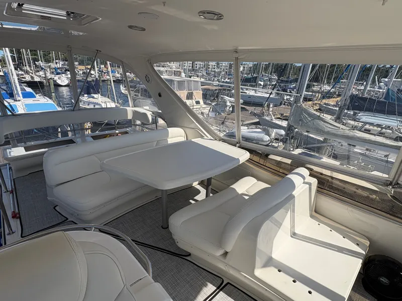 Slide: The Image of Interior of a 2000 Sea Ray 560 Sedan Bridge with white seating and table, surrounded by yachts in a marina. - 10