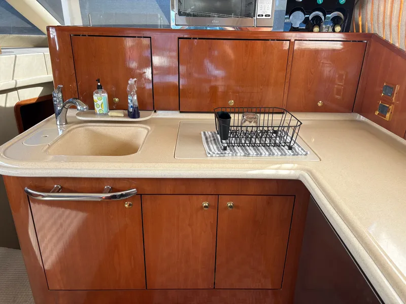 Slide: The Image of The galley of a 2000 Sea Ray 560 Sedan Bridge with a sink and wooden cabinets. - 34