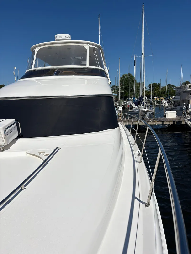 Slide: The Image of 2000 Sea Ray 560 Sedan Bridge in a marina, featuring a sleek white deck and clear blue sky. - 3