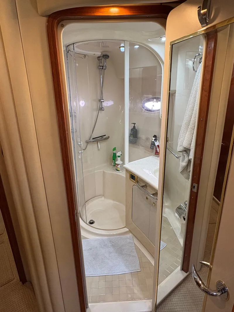 Slide: The Image of The image shows a bathroom on a 2000 Sea Ray 560 Sedan Bridge. It features a shower with glass door, sink, and towels. - 23