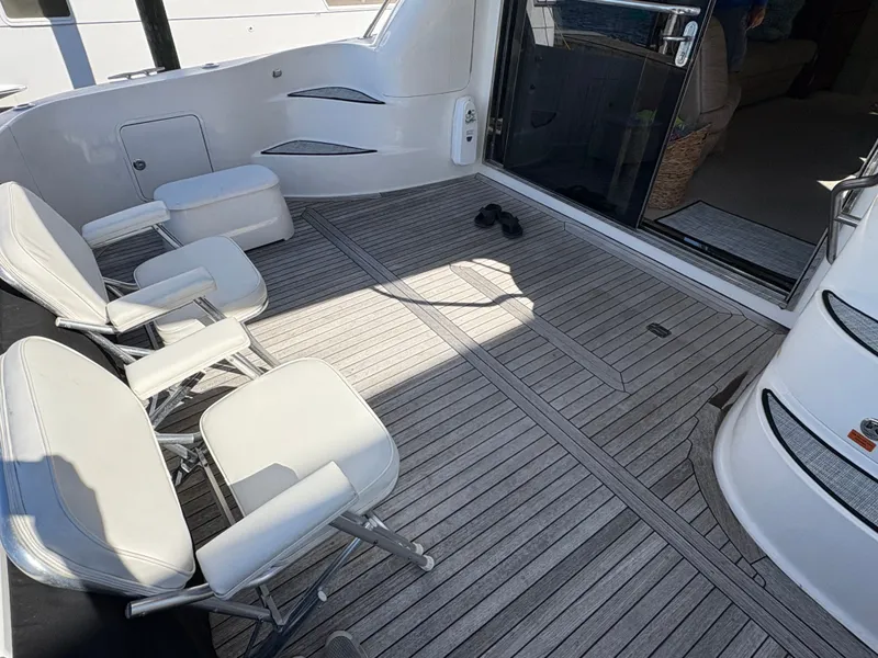 Slide: The Image of The image shows the deck of a 2000 Sea Ray 560 Sedan Bridge with white folding chairs. - 18
