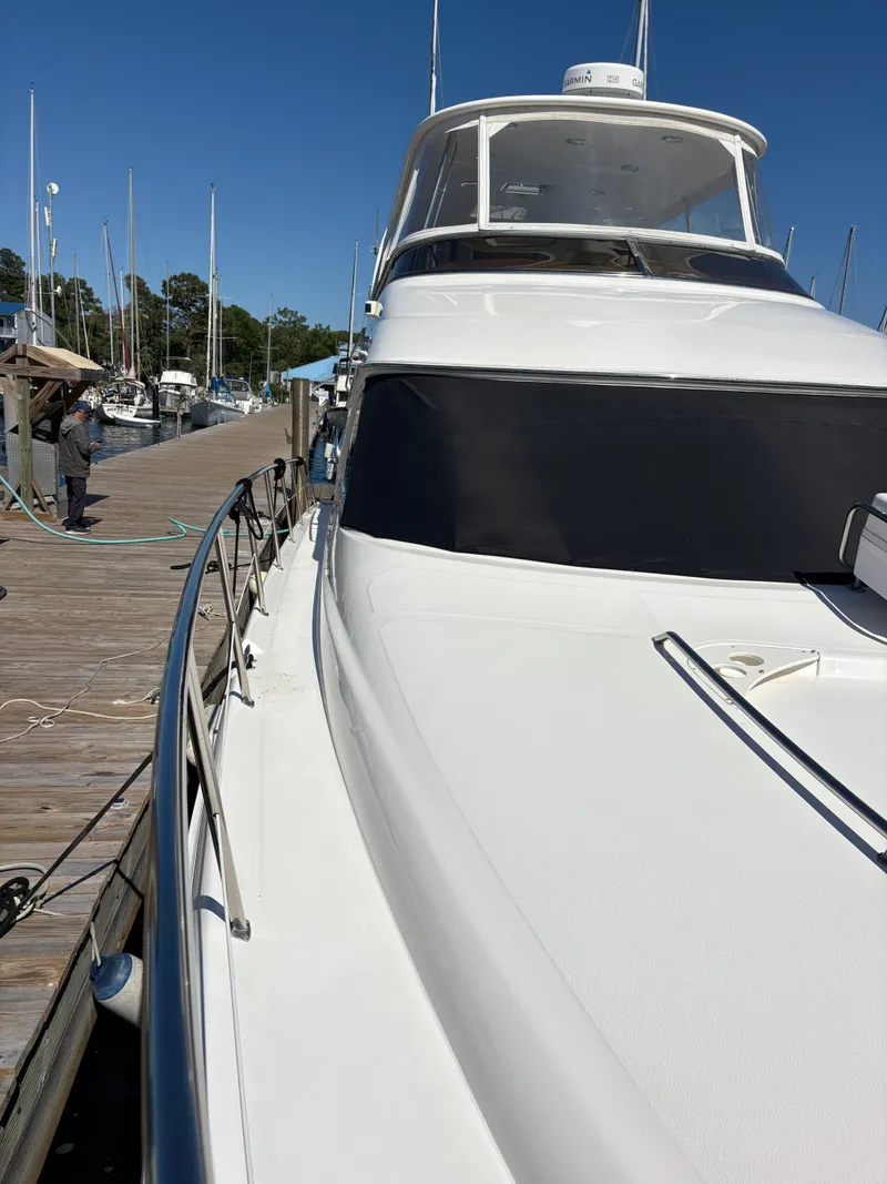 Slide: The Image of The 2000 Sea Ray 560 Sedan Bridge is docked at a wooden pier. It features a sleek, white design. - 4