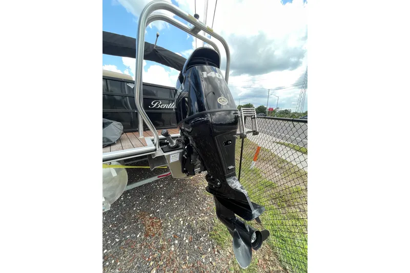 Slide: The Image of 2021 Bentley Pontoons 240 CRUISE with powerful outboard motor, parked near a fence. - 2