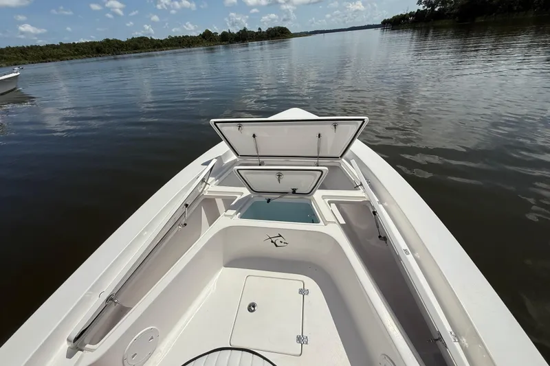 Slide: The Image of 2024 Piranha Boatworks Casador B2250 on calm water, open storage compartments visible. - 32