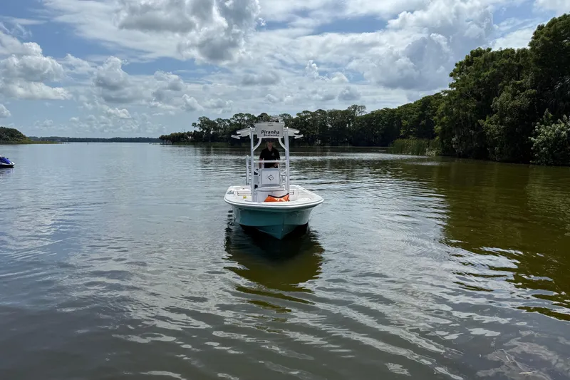 Slide: The Image of 2024 Piranha Boatworks Casador B2250 on a serene lake under cloudy skies. - 28