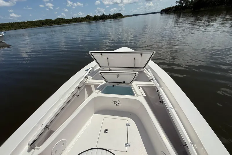 Slide: The Image of 2024 Piranha Boatworks Casador B2250 on calm water, showcasing open storage compartments. - 31