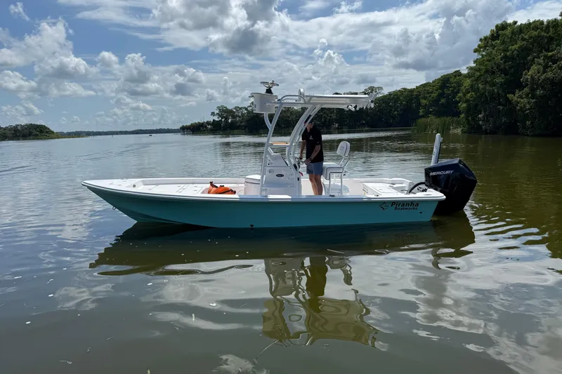Slide: The Image of 2024 Piranha Boatworks Casador B2250 on a calm lake under a cloudy sky. - 18