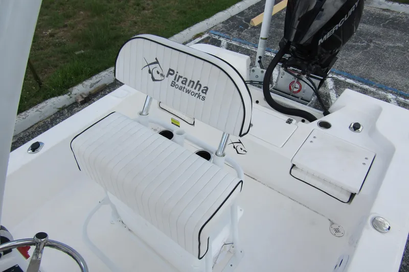 Slide: The Image of 2024 Piranha Boatworks Casador B2250 interior with white seating and Mercury engine. - 13