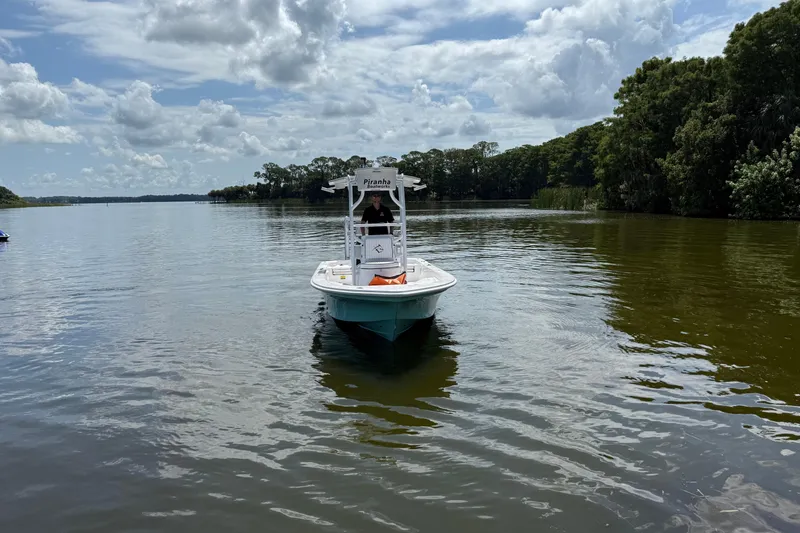 Slide: The Image of 2024 Piranha Boatworks Casador B2250 on a serene lake under cloudy skies. - 29
