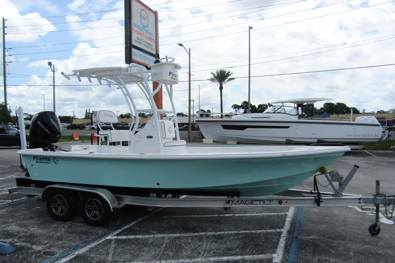Slide: The Image of 2024 Piranha Boatworks Casador B2250 on trailer at dealership, under cloudy sky. - 2