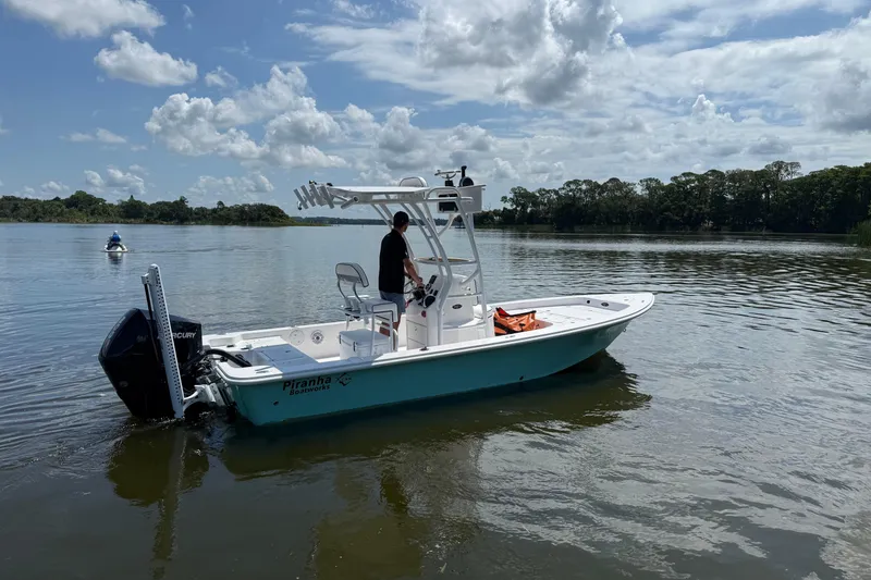 Slide: The Image of 2024 Piranha Boatworks Casador B2250 on a serene lake under cloudy skies. - 26