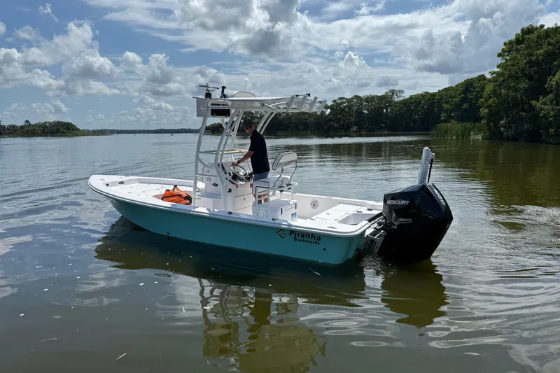 Slide: The Image of 2024 Piranha Boatworks Casador B2250 on a calm lake under a cloudy sky. - 20