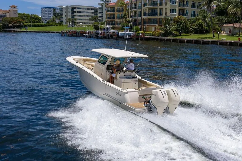 Slide: The Image of 2021 Scout 305 LXF boat cruising on a scenic waterfront with modern buildings. - 9