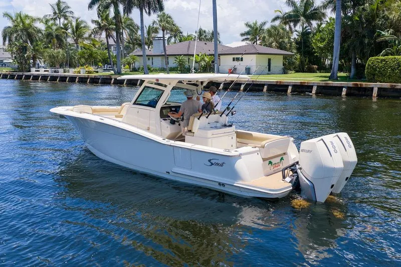 Slide: The Image of 2021 Scout 305 LXF boat cruising on a scenic waterway with palm trees. - 12