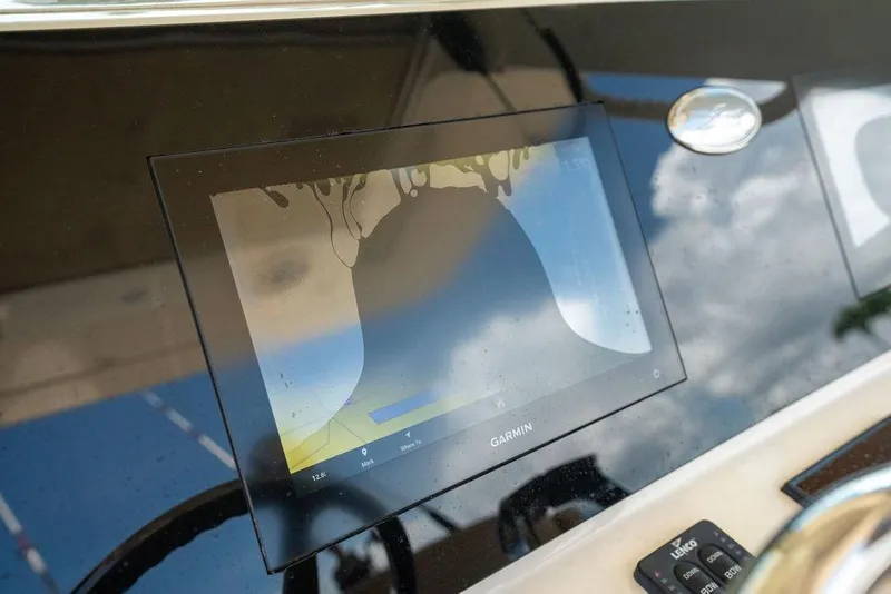 Slide: The Image of Garmin display on 2021 Scout 305 LXF boat dashboard, reflecting sky and clouds. - 31