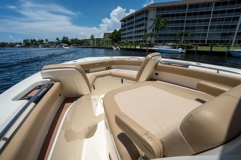 Slide: The Image of 2021 Scout 305 LXF boat interior with beige seating, dockside view. - 16