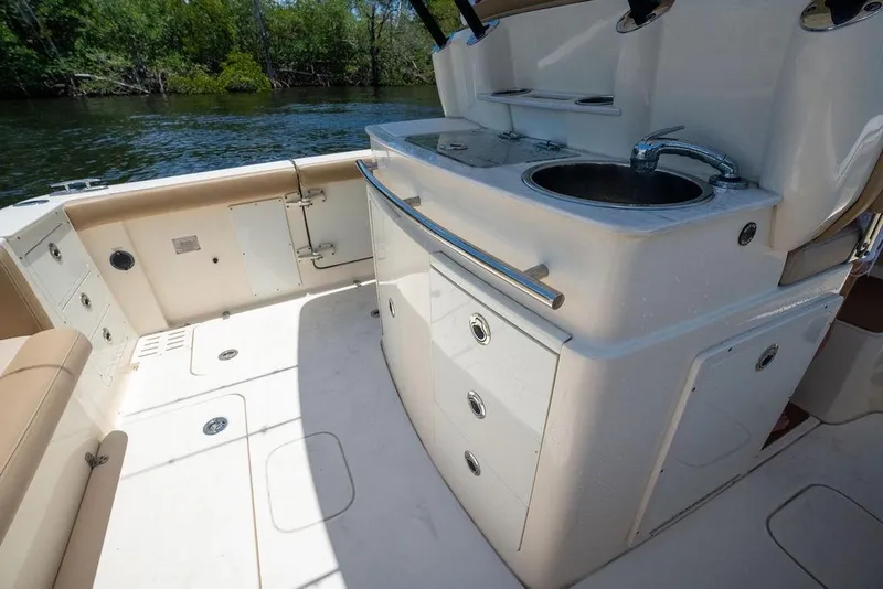 Slide: The Image of 2021 Scout 305 LXF boat interior with sink and storage, near water. - 27