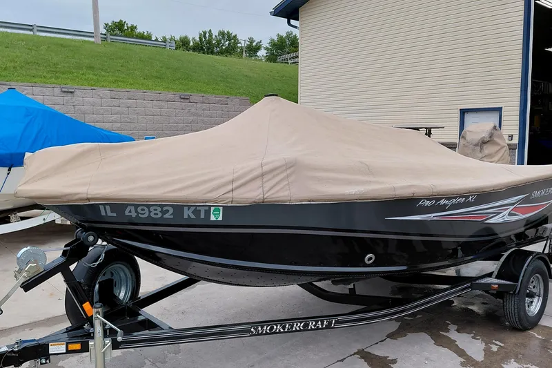 The Image of 2013 Smoker Craft Pro Angler XL 161 boat covered on trailer, parked outdoors. - 0