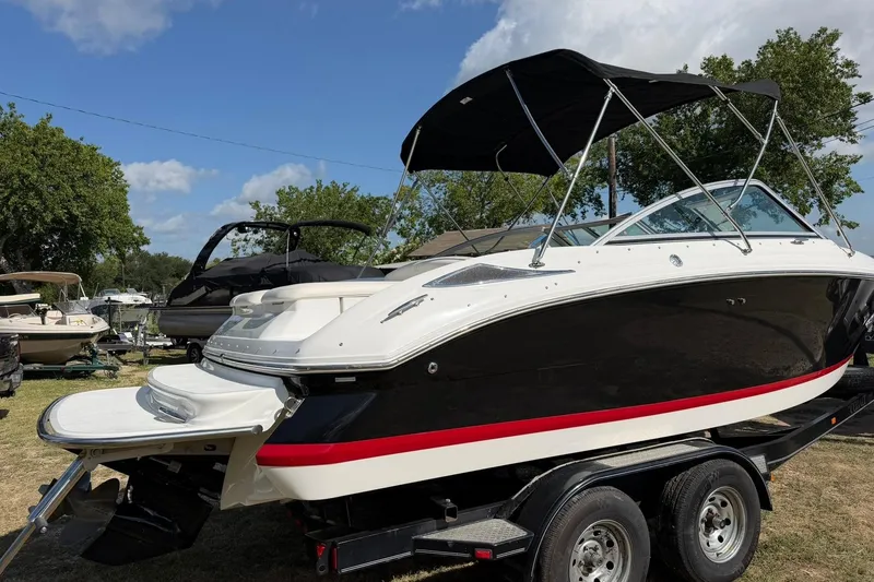 Slide: The Image of 2007 Cobalt 212 boat with black hull and red stripe on trailer, under blue sky. - 12
