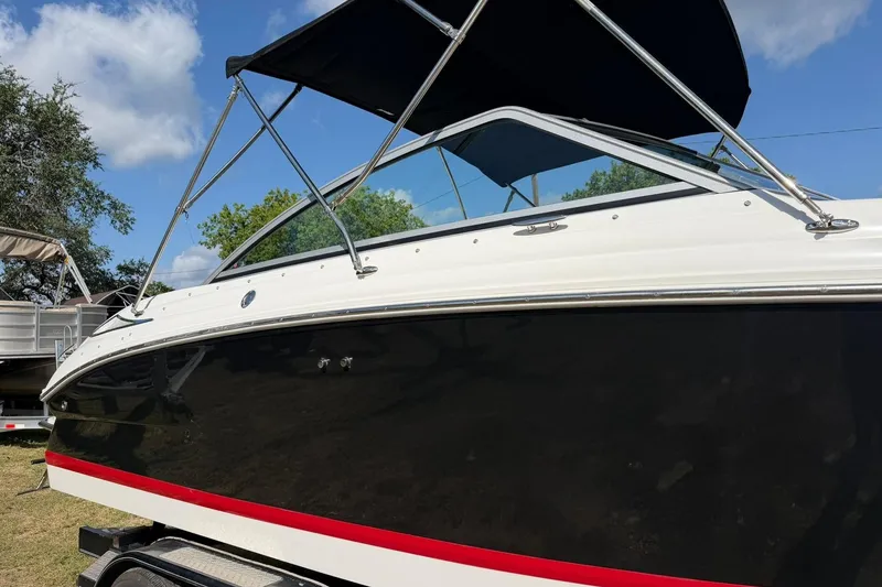 Slide: The Image of 2007 Cobalt 212 boat with black hull and red stripe, parked on a trailer. - 11