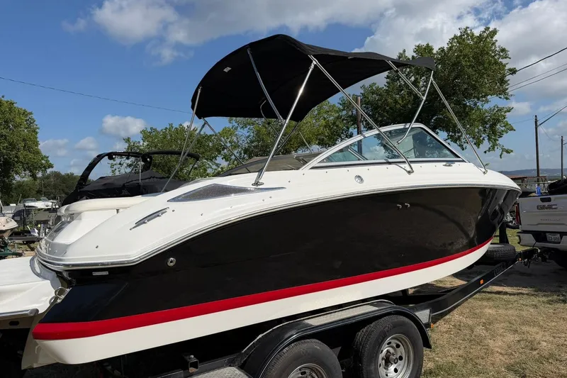 Slide: The Image of 2007 Cobalt 212 boat on trailer, black and white with red stripe, under sunny sky. - 13