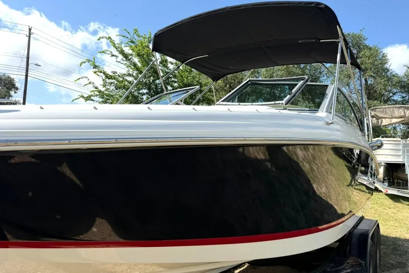 Slide: The Image of 2007 Cobalt 212 boat with black hull and canopy, parked outdoors under blue sky. - 17