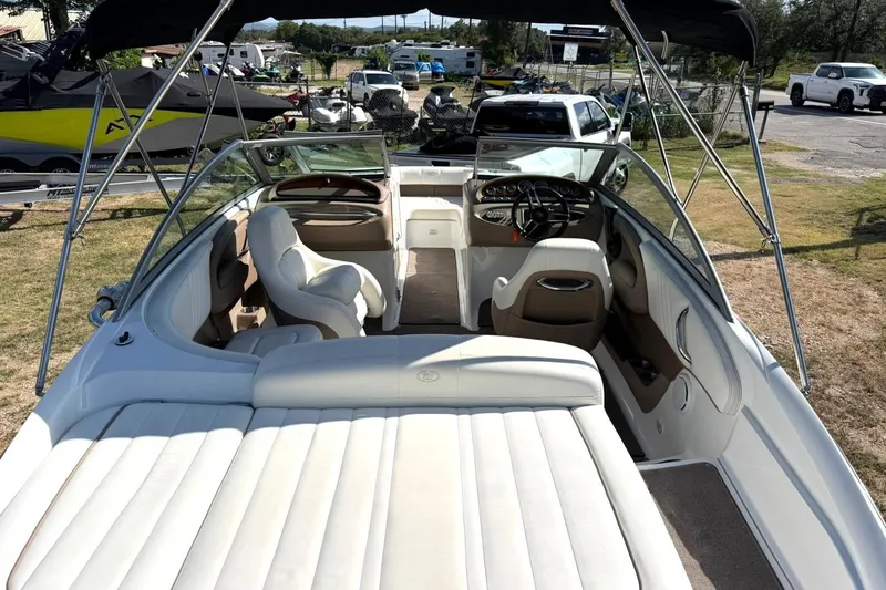 Slide: The Image of 2007 Cobalt 212 boat interior with white seating and steering wheel, parked outdoors. - 24