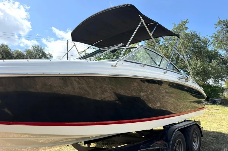 Slide: The Image of 2007 Cobalt 212 boat with black hull and canopy on a trailer, outdoors. - 18