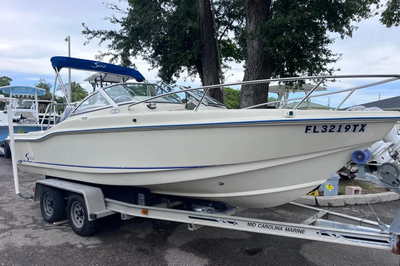 Slide: The Image of 2001 Scout 202 Dorado boat on trailer, parked outdoors with trees in background. - 1