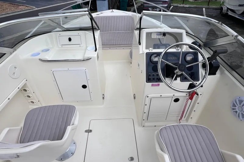 Slide: The Image of Interior view of a 2001 Scout 202 Dorado boat, featuring steering wheel and seating. - 24