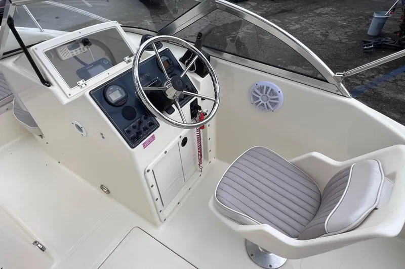 Slide: The Image of Interior of a 2001 Scout 202 Dorado boat featuring steering wheel and seating. - 27