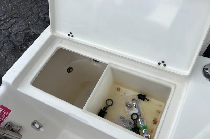 Slide: The Image of Open storage compartment on a 2001 Scout 202 Dorado boat with tools inside. - 22