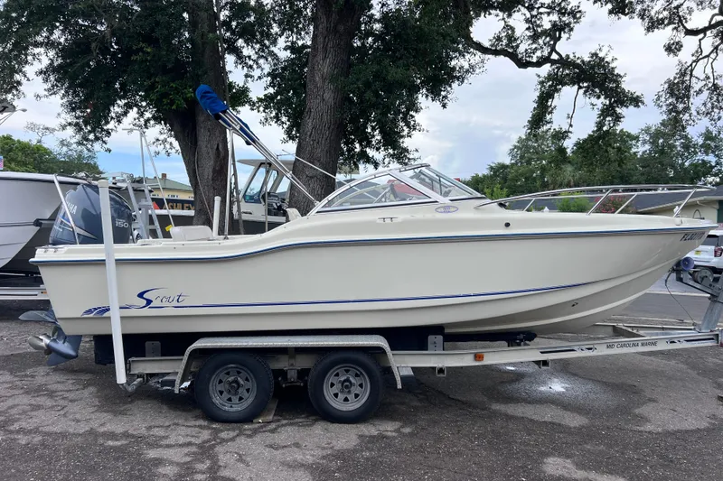 The Image of 2001 Scout 202 Dorado boat on trailer, parked outdoors under trees. - 0